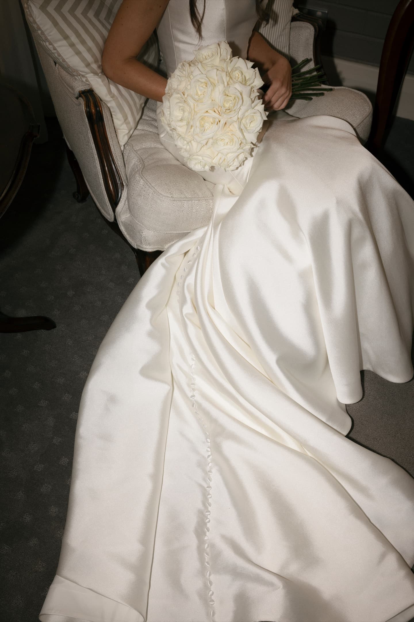 Bride seated in the bridal suite with a dome bouquet of white and cream roses, designed by La Fleur Botanica